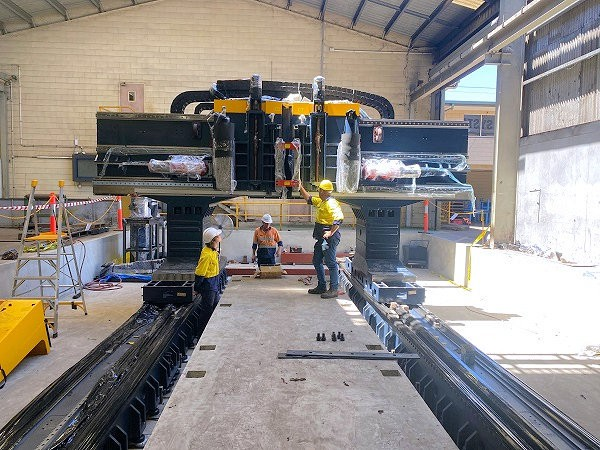 CNC Machinery technicians installing a large gantry machine tool in a workshop